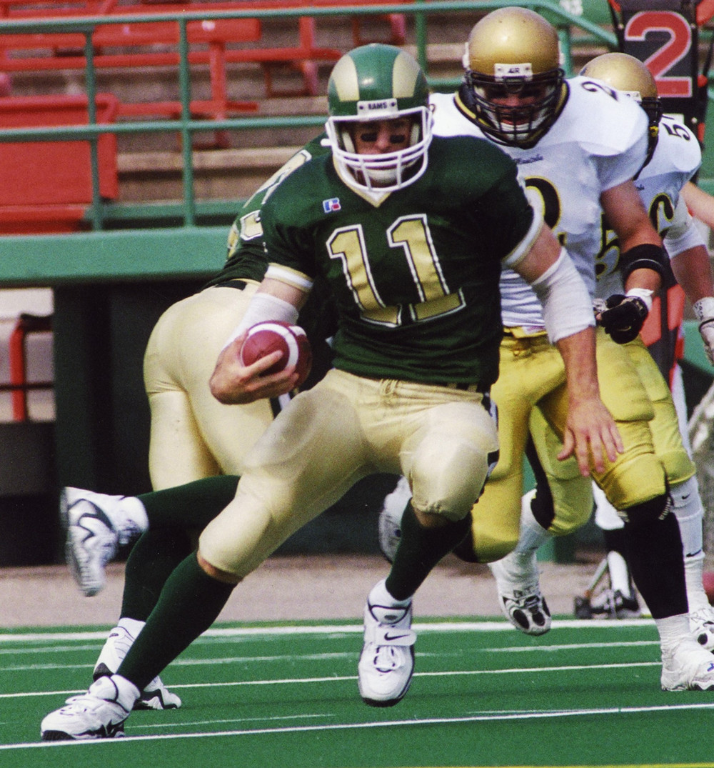 A football player wearing number 11 runs with a ball in his hand.