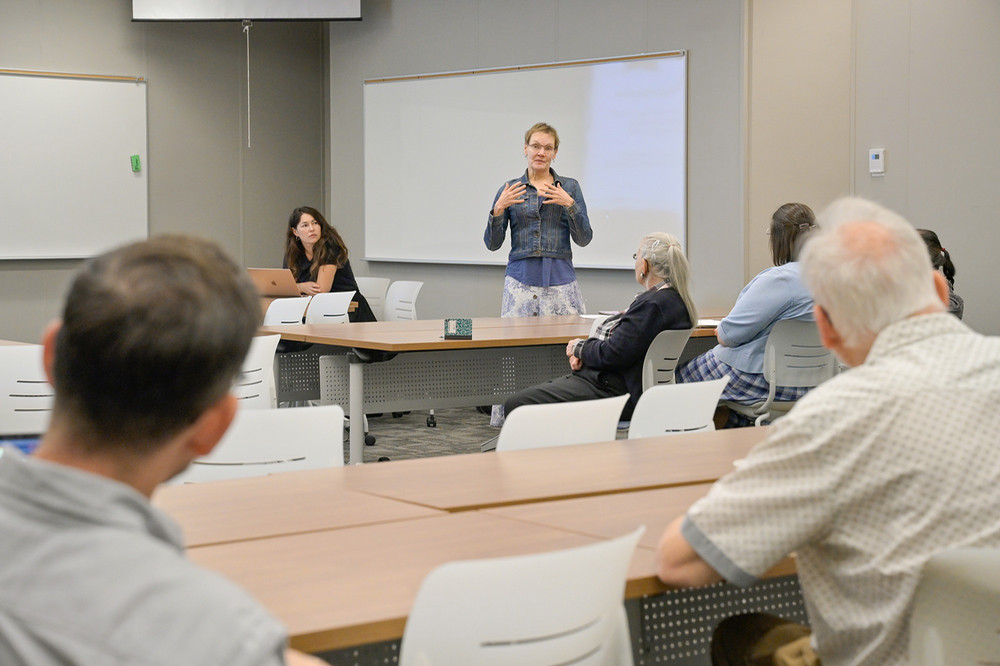 A woman addresses a small group listening intently