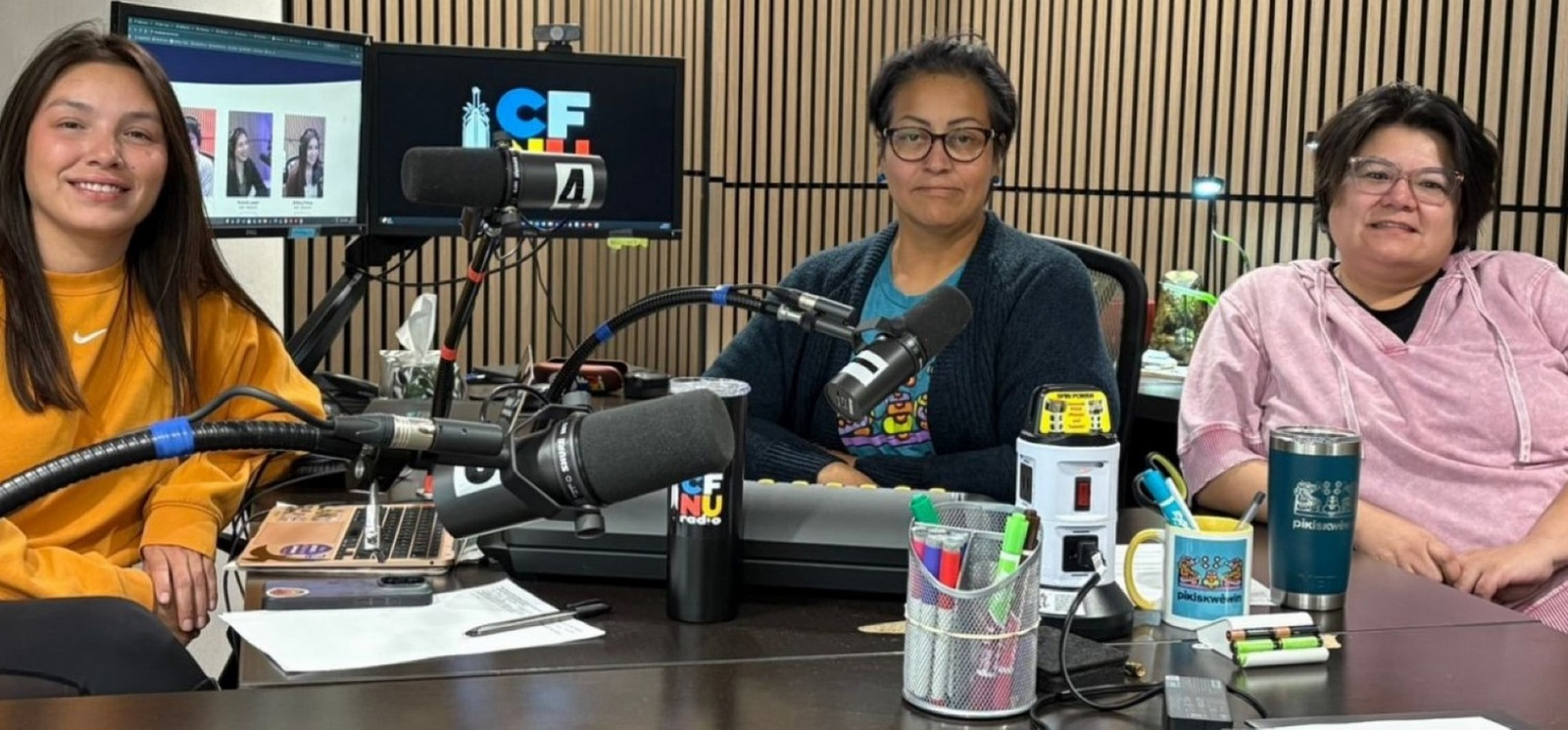 Three individuals sitting down in a radio station studio