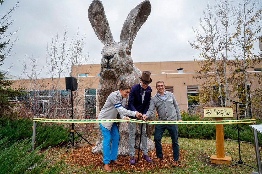 two people standing near rabbit sculpture