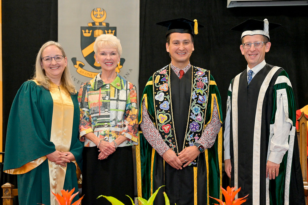 four people posing on stage at convocation