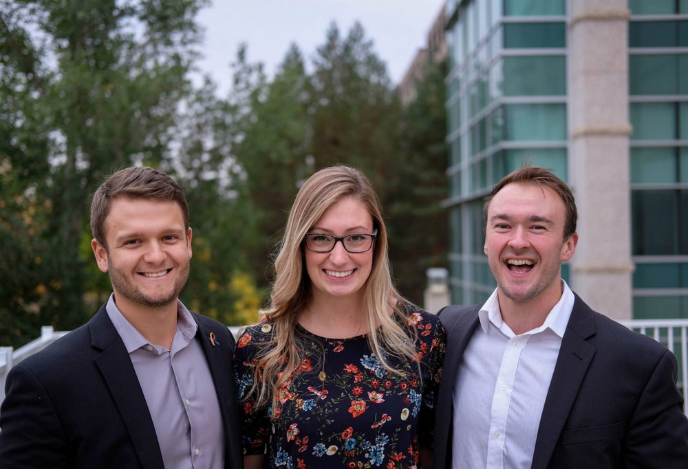 three people posing outside