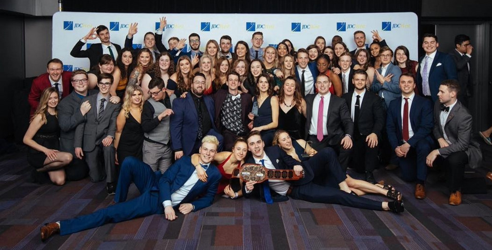a large group of students standing in front of a large banner