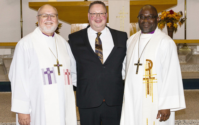 three smiling men standing on a church altar