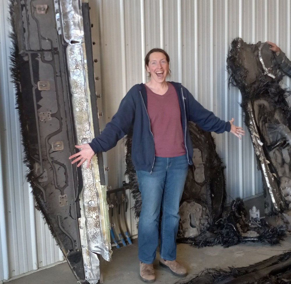 a person smiling and posing with some pieces of art