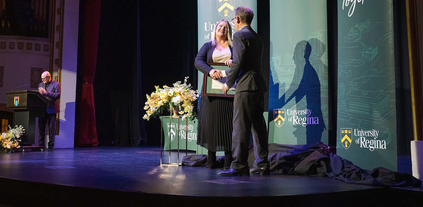 three people standing on a stage