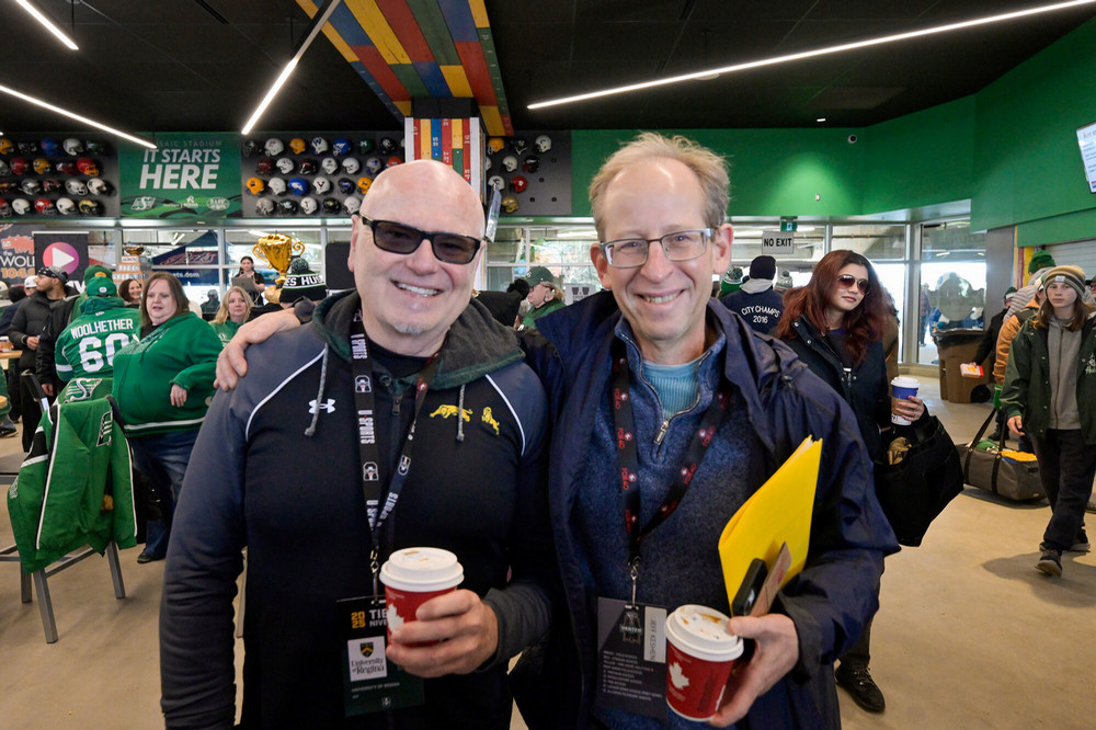 Two men face the camera with big smiles. 