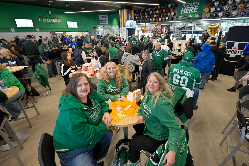 A room full of people wearing green Saskatchewan Roughriders jerseys. 