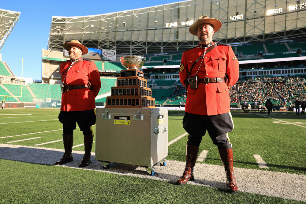 Two RCMP officers pose near a trophy in a football stadium.