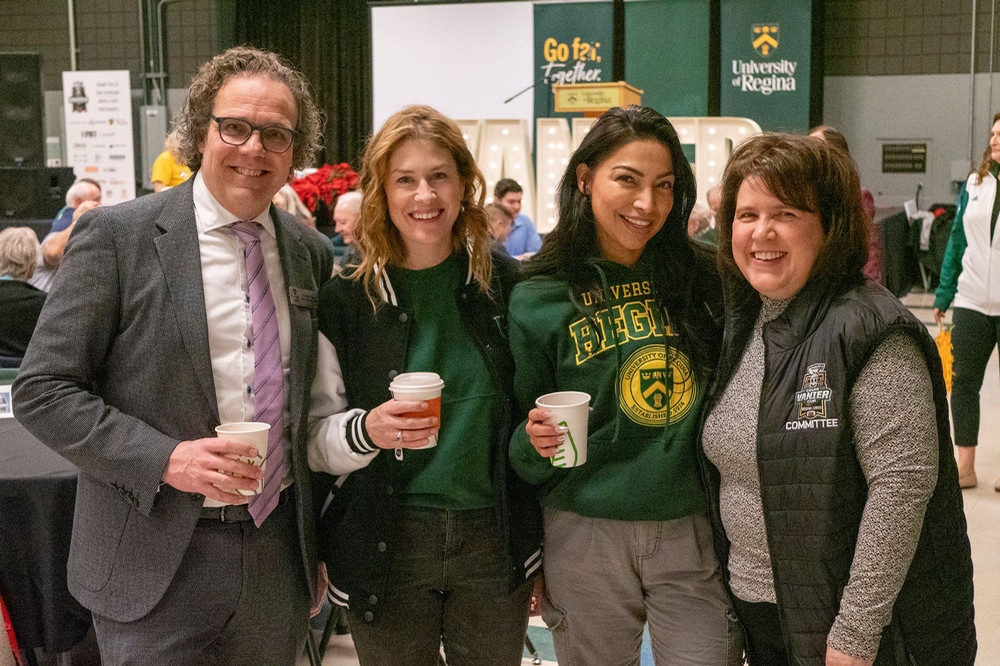 Four people drinking coffee and smiling.