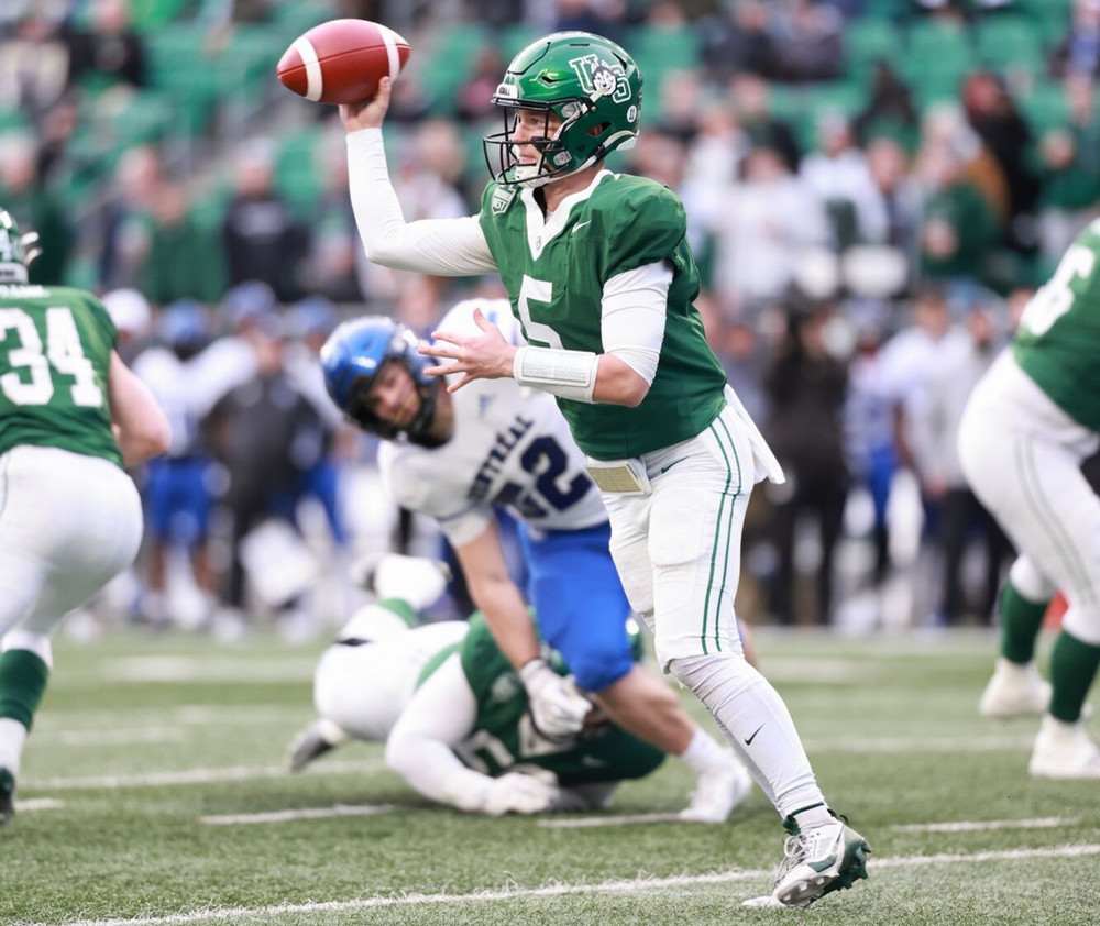 A quarterback in a green jersey throws a football during a game.