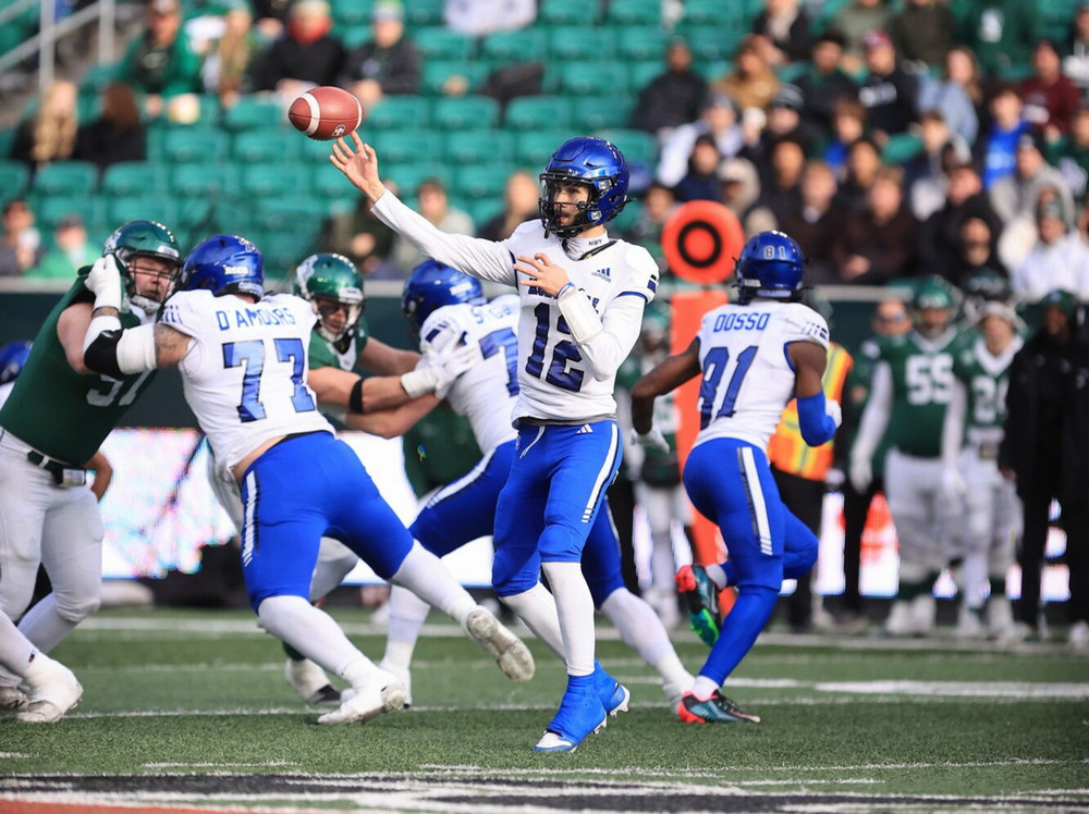 The quarterback of a team in white throws the ball.