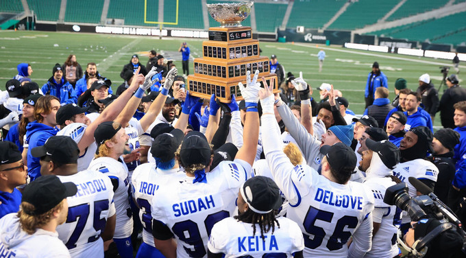 Football players encircling and hoisting a trophy.