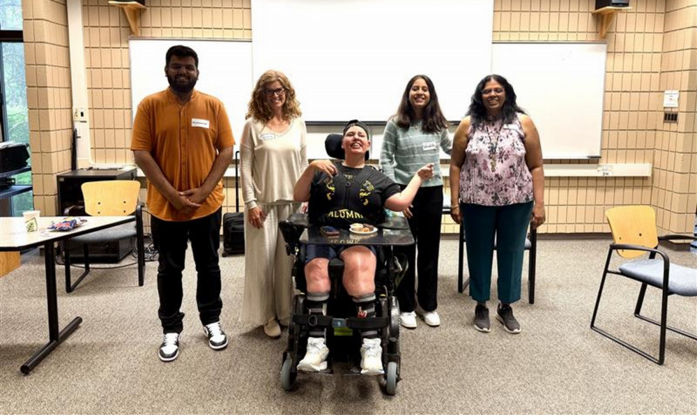 : Five participants in the accessibility consultation process stand and sit together in a classroom during the June 18 afternoon session 