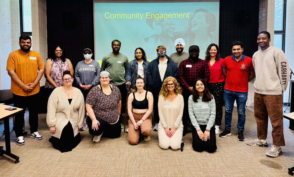 A large, diverse group of U of R community members pose and smile during the June 18 morning community engagement session on accessibility