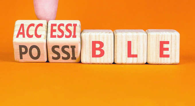 A conceptual image symbolizing the shift from impossible to possible. A hand flips wooden blocks to change the word 'IMPOSSIBLE' to 'POSSIBLE', revealing the letters 'ACC' to also spell 'ACCESSIBLE', representing the removal of barriers to create new opportunities.