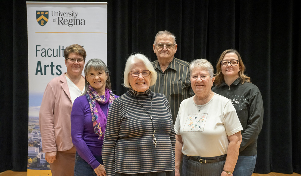 a group of six people standing in front of a banner