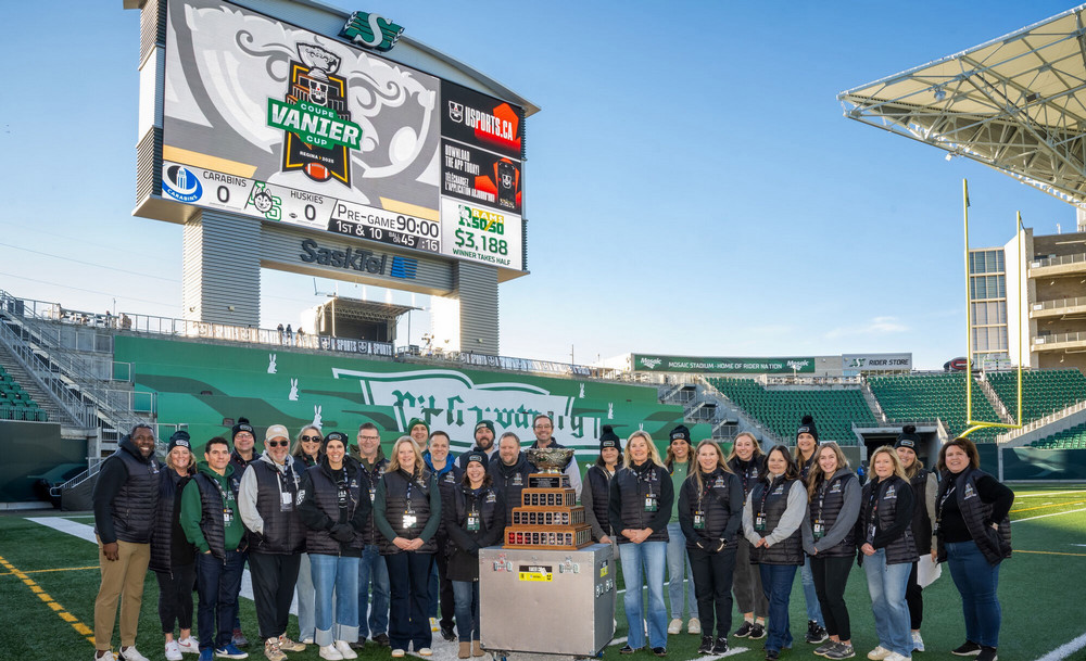 People assembled around a trophy on a football field.