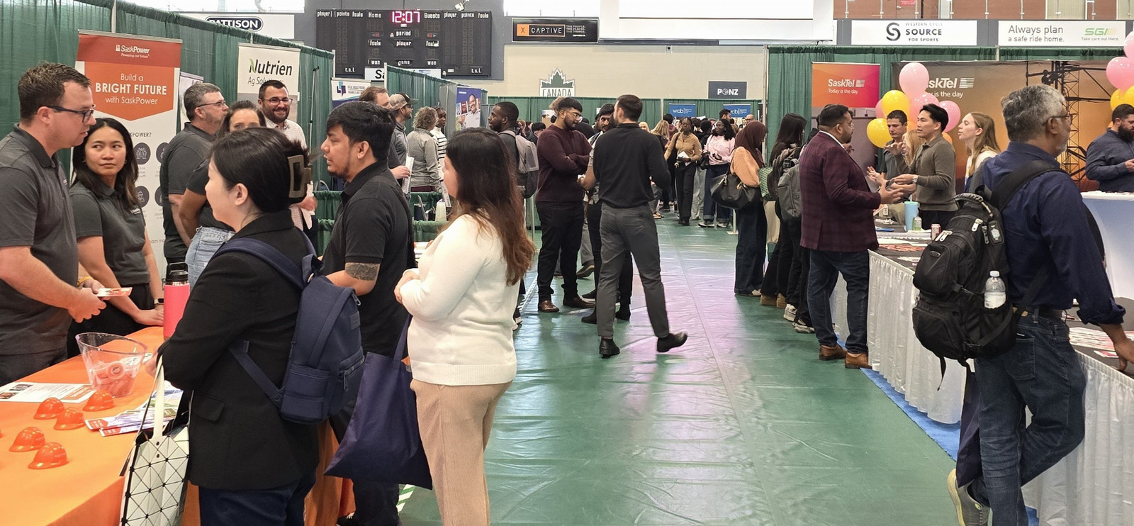 people at tables in a gymnasium speaking with students