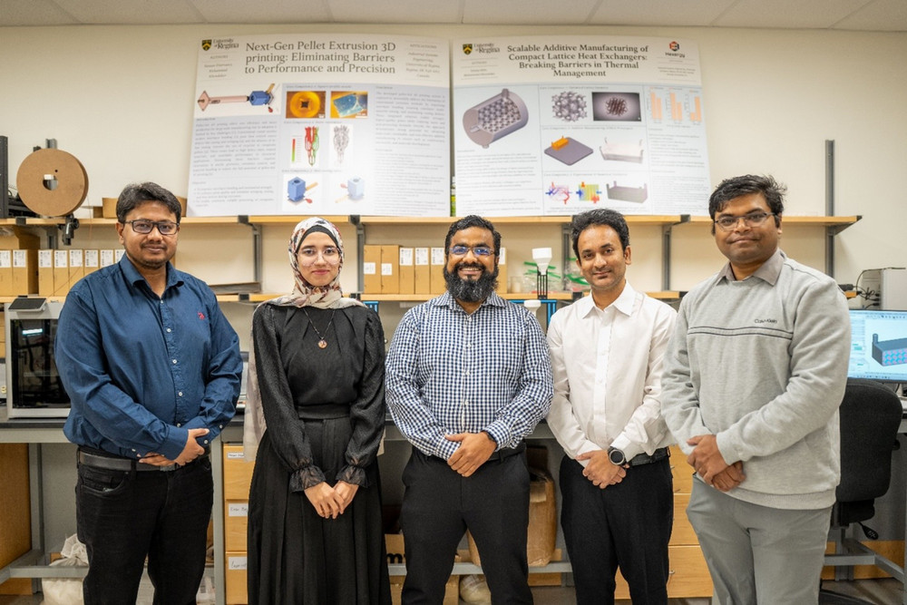 A group portrait of Professor Mohammad Khondoker standing confidently with four graduate student researchers in the Additive Manufacturing Research Lab, backed by scientific posters detailing their work.