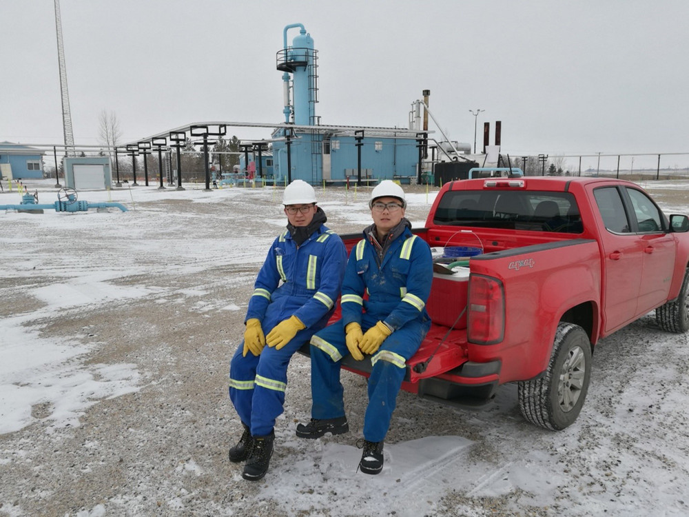 A candid shot of a U of R student researchers actively working on equipment on the back of a red pickup truck in a snowy field setting