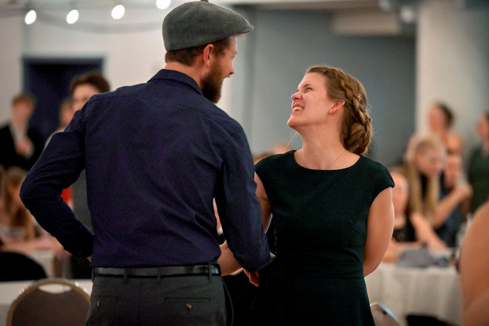 Two people share a smile while dancing together at the MAP Big Band Dance, surrounded by other dancers.