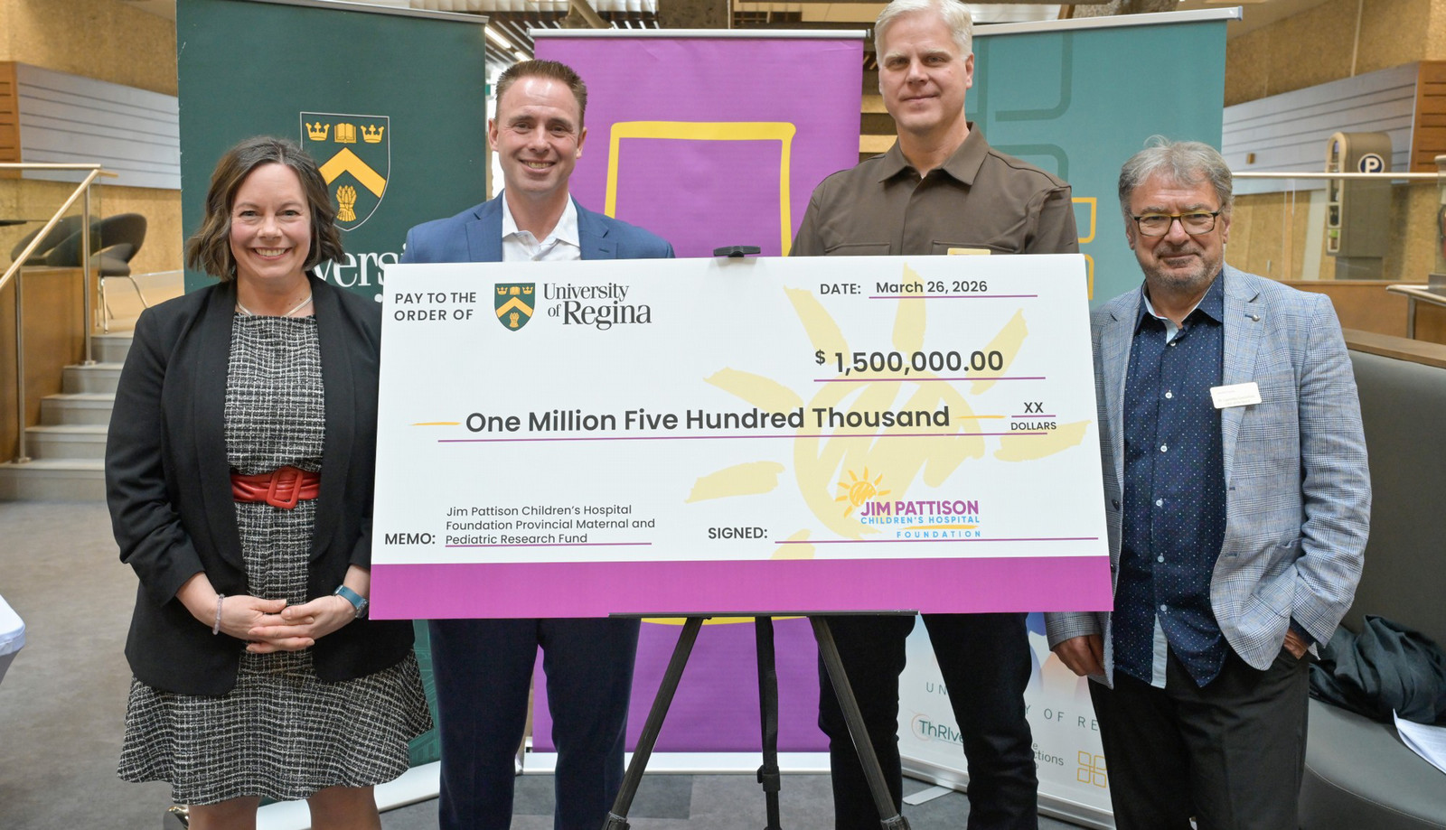 four people on stage, one holding a large cheque