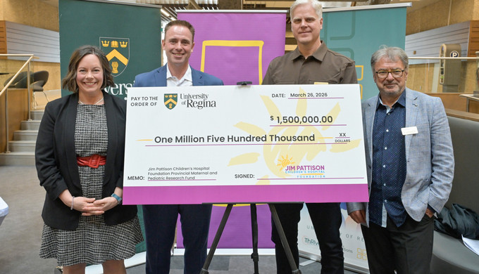 four people on stage, one holding a large cheque