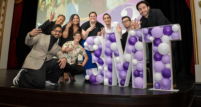 eight people smiling and posing on a stage