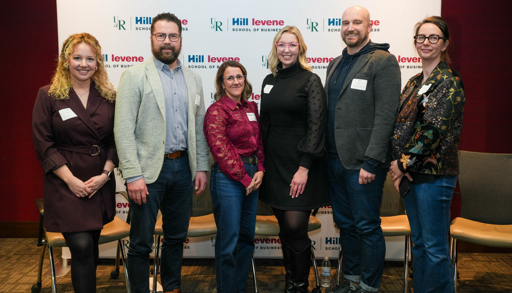 A panel of industry experts stands together at the Innovation Challenge 2026 opening reception, posed in front of a University of Regina Hill Levene School of Business backdrop. 