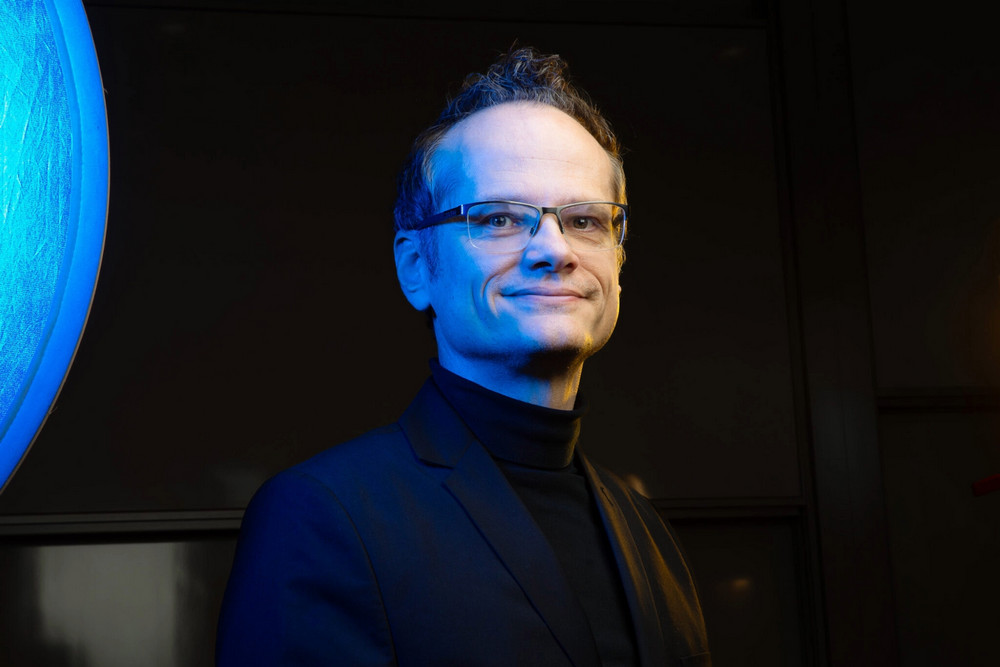  Mark Daley, Chief AI Officer at Western University, photographed in front of a large illuminated digital display in a dark-lit setting
