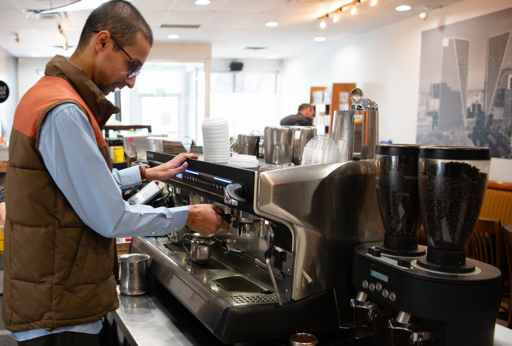a man behind a counter using a coffee machine