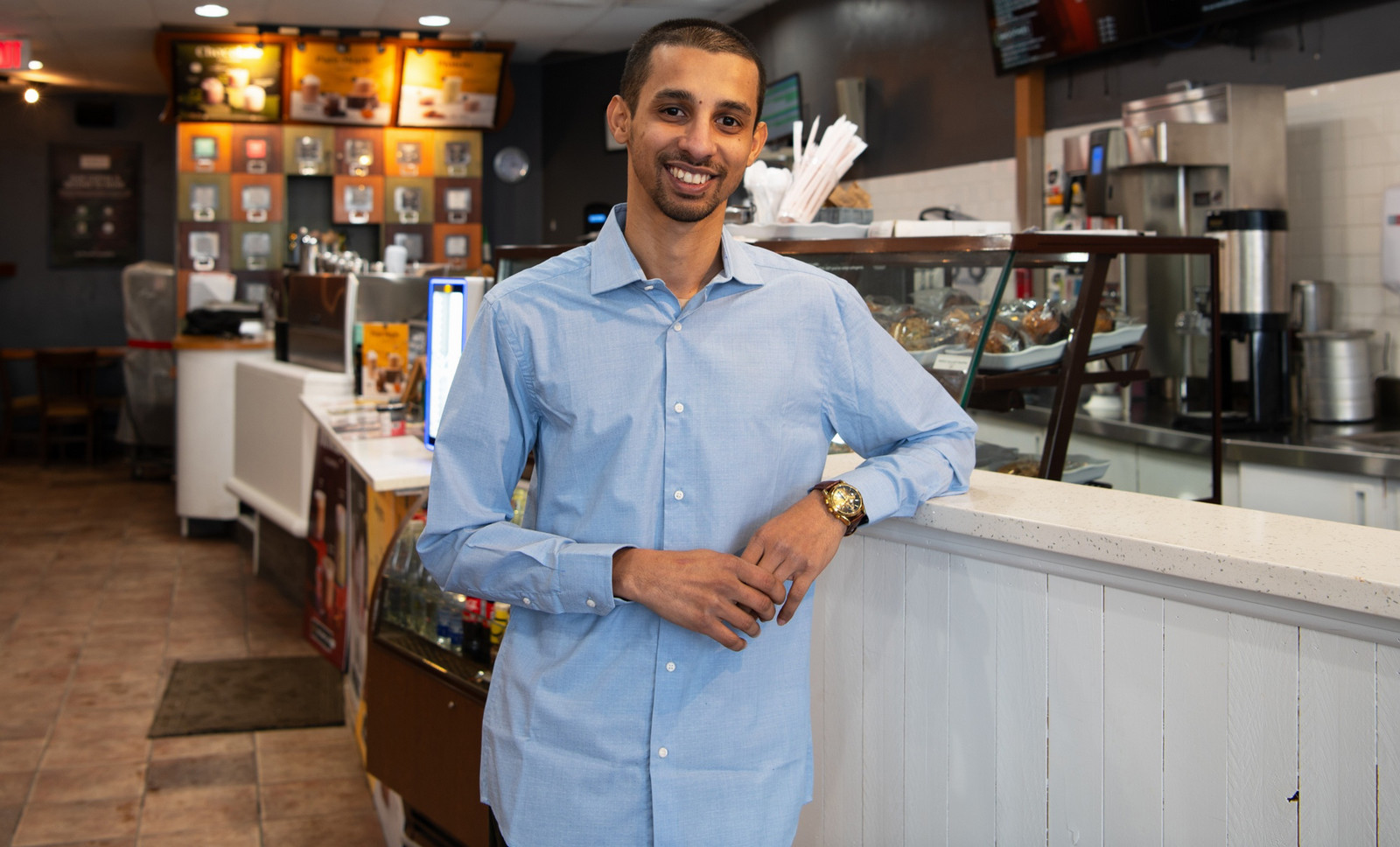 a smiling man leaning against a counter