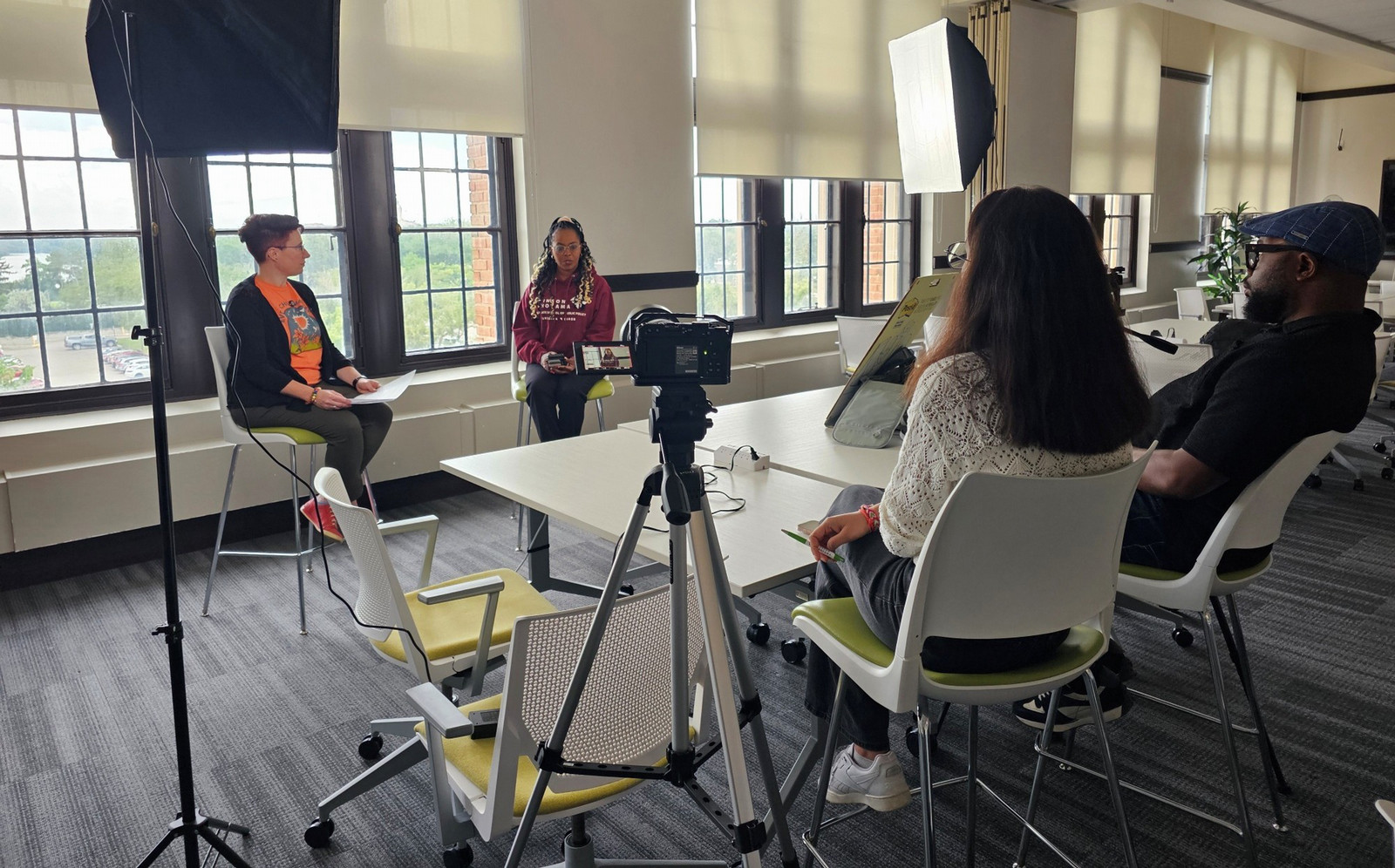 Members of the EDI Digital Resource Hub project team film interviews around a table in a bright meeting room, using professional lighting and a camera.