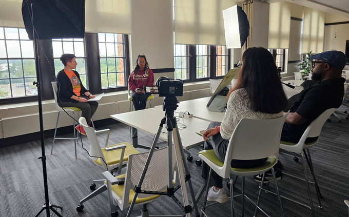 Members of the EDI Digital Resource Hub project team film interviews around a table in a bright meeting room, using professional lighting and a camera.