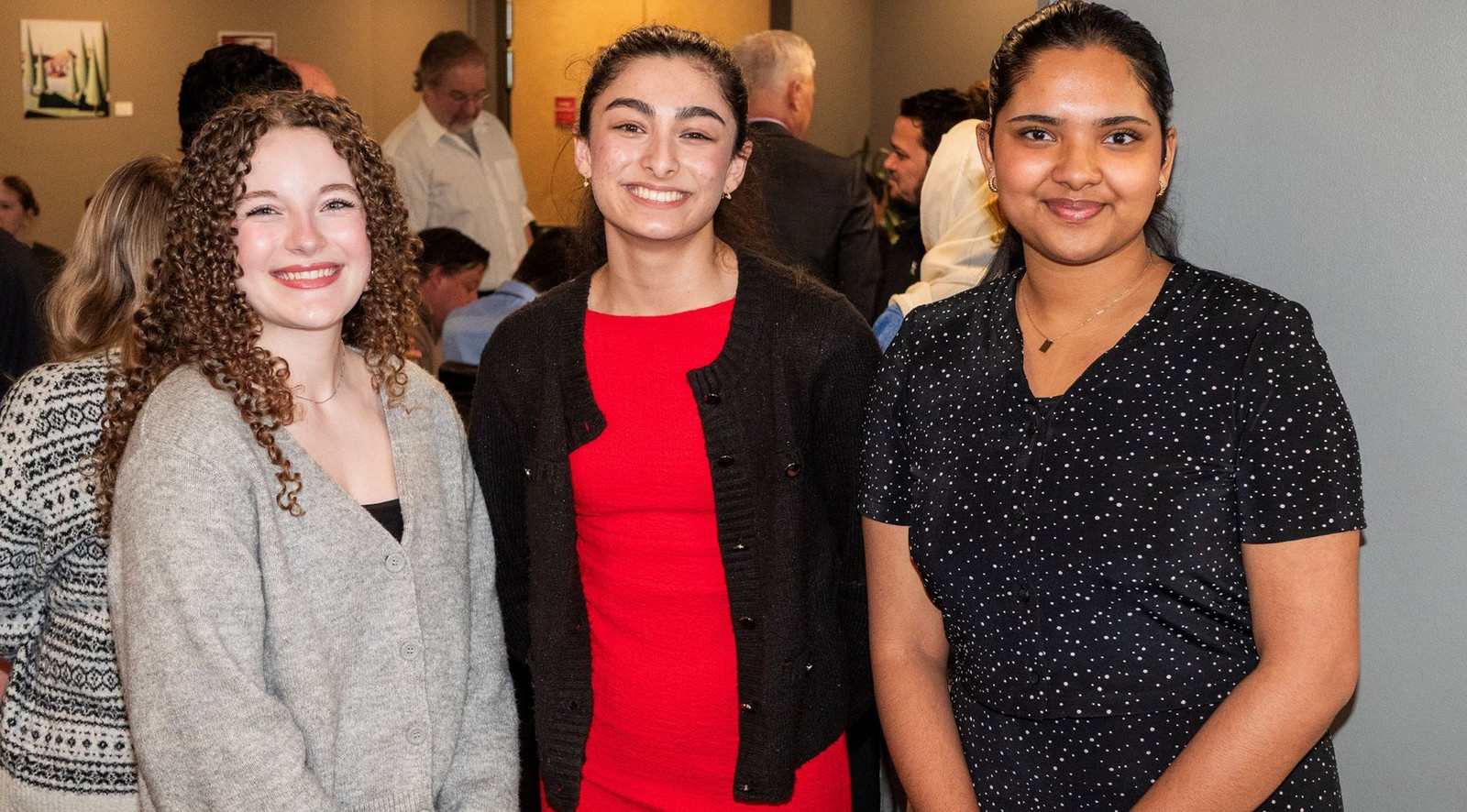 Three women stand smiling