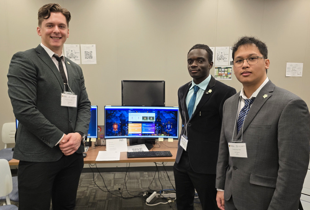 Three people stand in professional attire in a computer lab