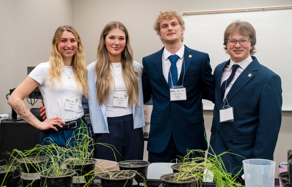 Four people stand smiling together in professional attire