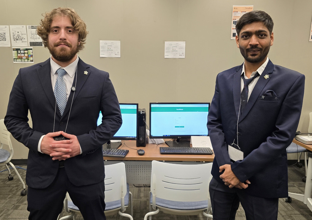 Two people wearing professional suits, stand confidently in a computer lab 