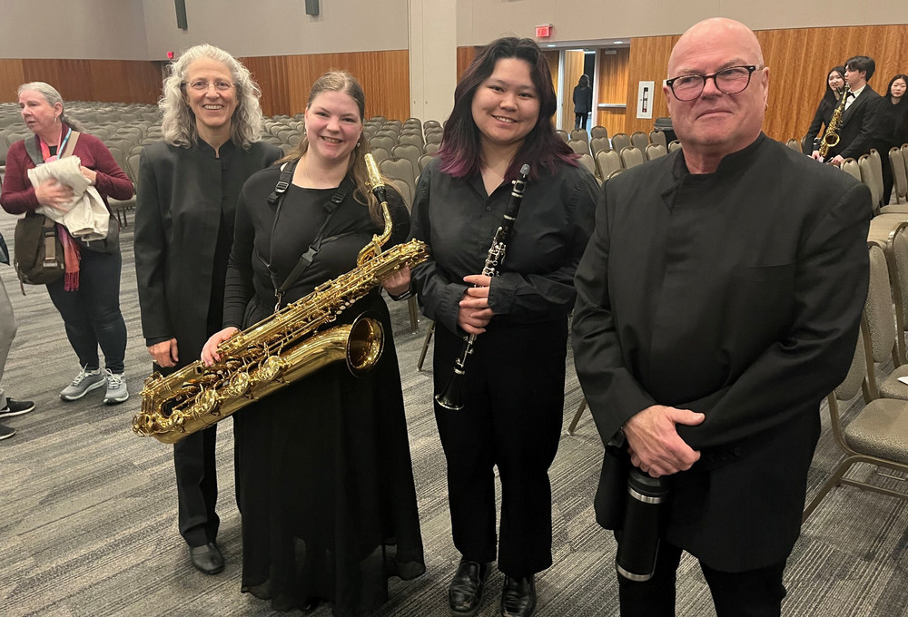 Four people stand together in a concert hall after a performance