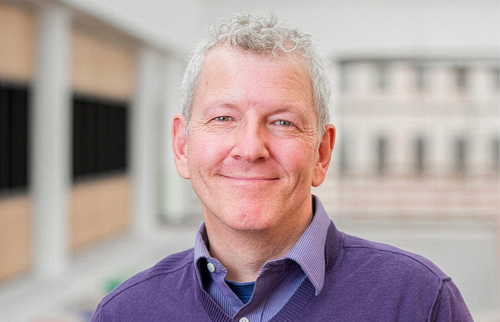 man smiling in a casual purple sweater