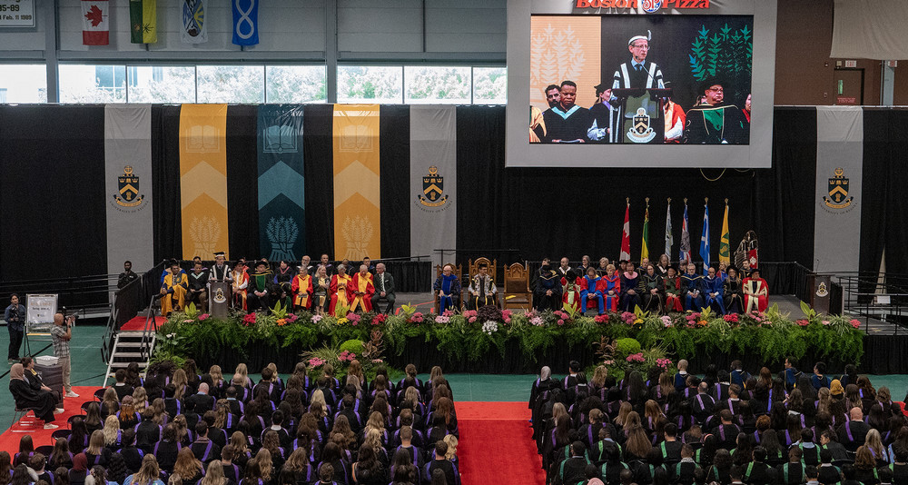 a crowded gymnasium with hundreds of graduates
