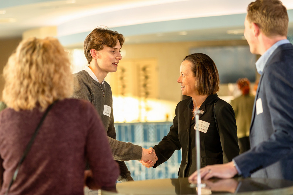 A student shakes hands with another person at a student recognition event