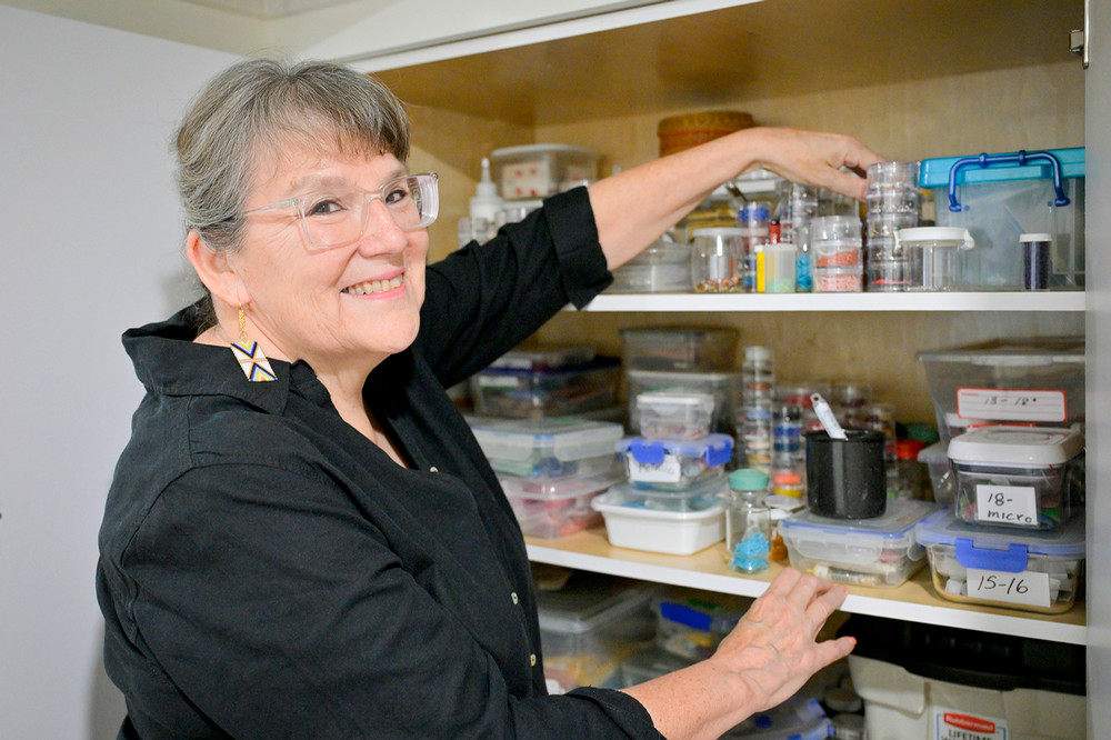 A woman reaches into a cupboard filled with art materials
