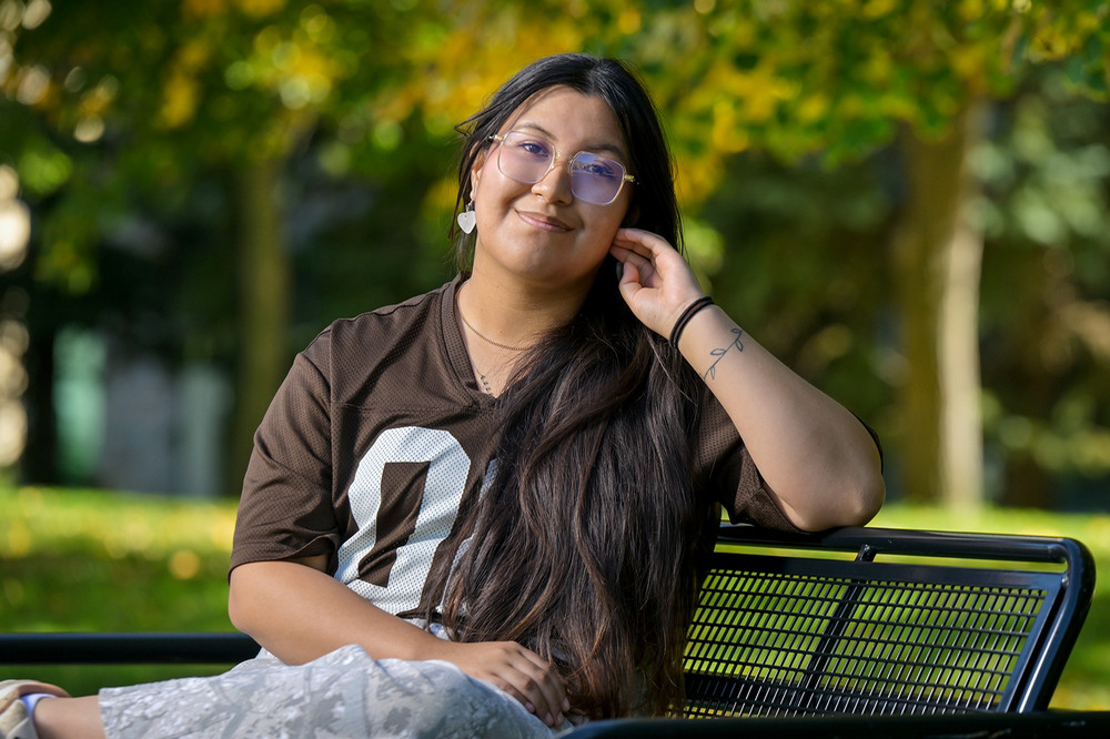 A person poses for a portrait and is surrounded by trees in the background. 
