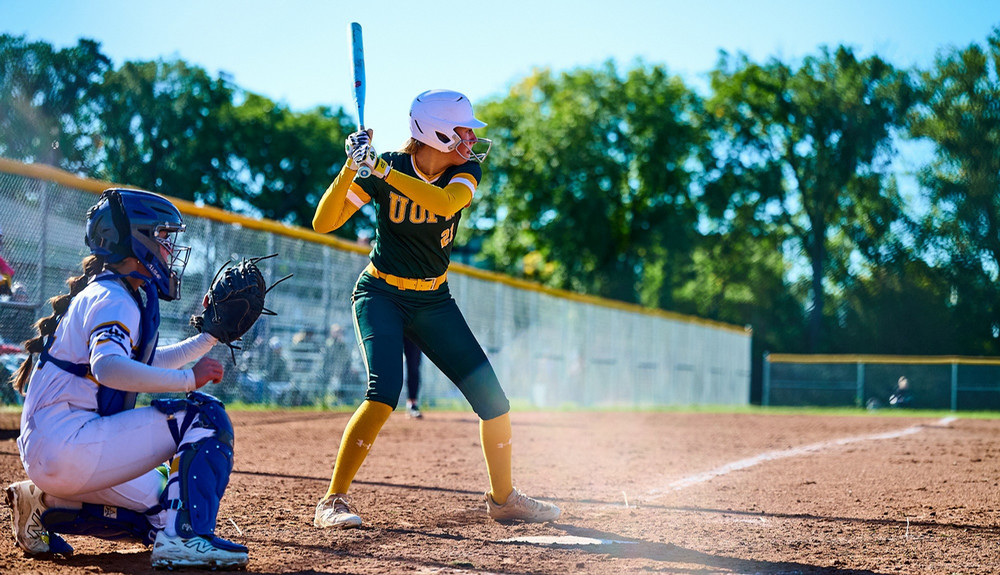 A young woman is at home plate preparing to hit a pitch.