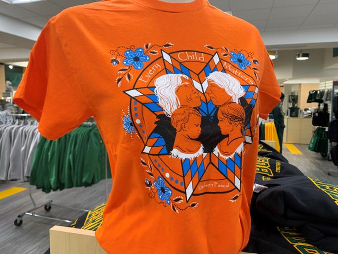 an orange t-shirt with an Indigenous design