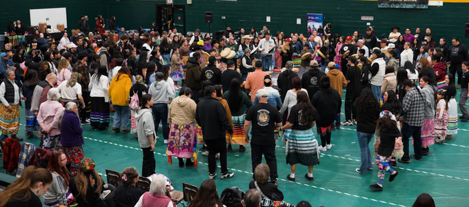 Large group of people gathered in a University of Regina gym for the ta-tawâw Student Centre round dance