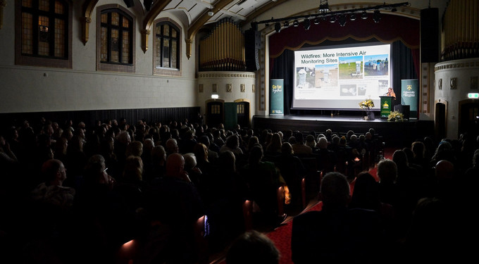 group of people in a hall looking at a person presenting