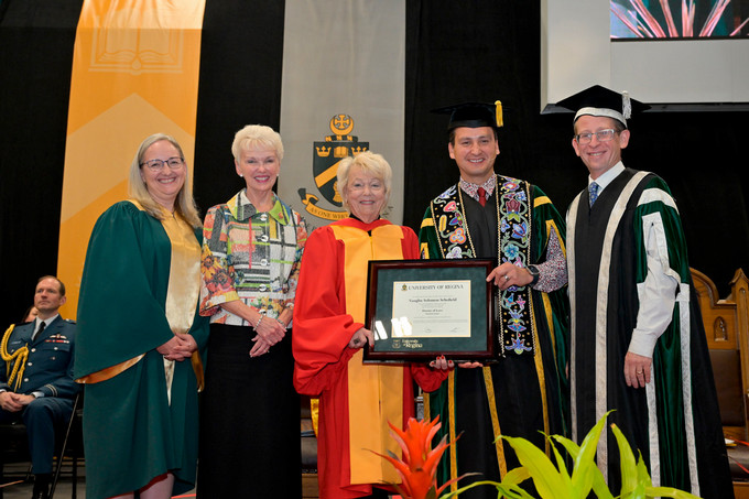 People standing and awarding degree certificate